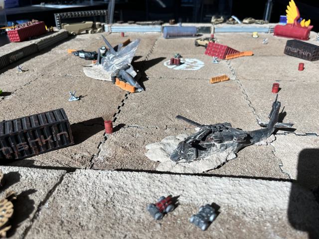 A downed helicopter and a wrecked jet beside a Mishkin container