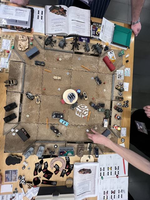 The arena seen from above, crowded with cars, dice and the rulebook